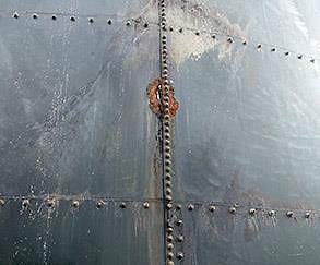 Corroded and holed storage tank wall